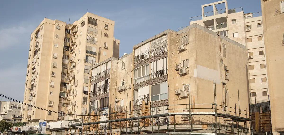 בנייני שיכון ישנים ומגדל משנות ה־70 ברובע א׳ באשדוד, עם פיגומים בבסיס.